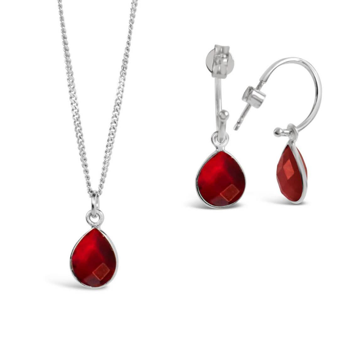 garnet charm necklace and drop hoop earrings on a white background