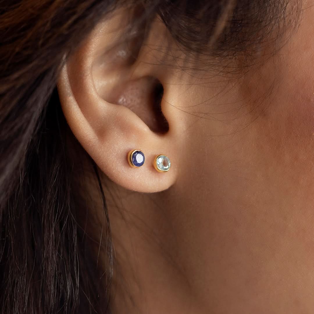 close up of model wearing blue topaz earrings in gold