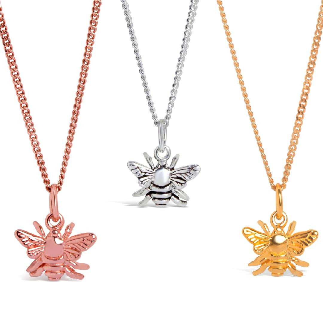 three bee pendants in silver, gold and rose gold on a white background