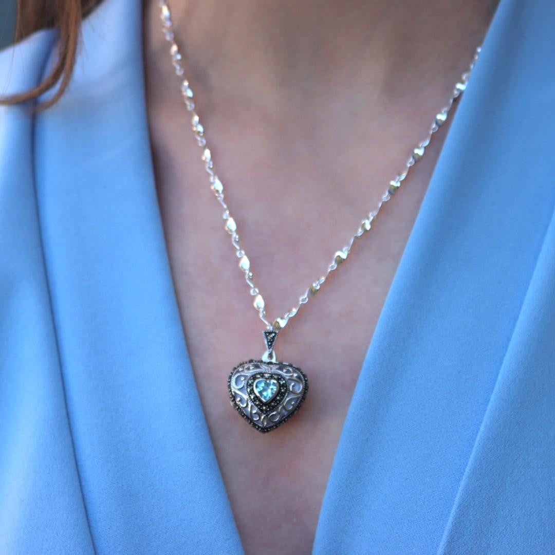 model in blue top wearing white gold vintage heart locket with topaz gemstone
