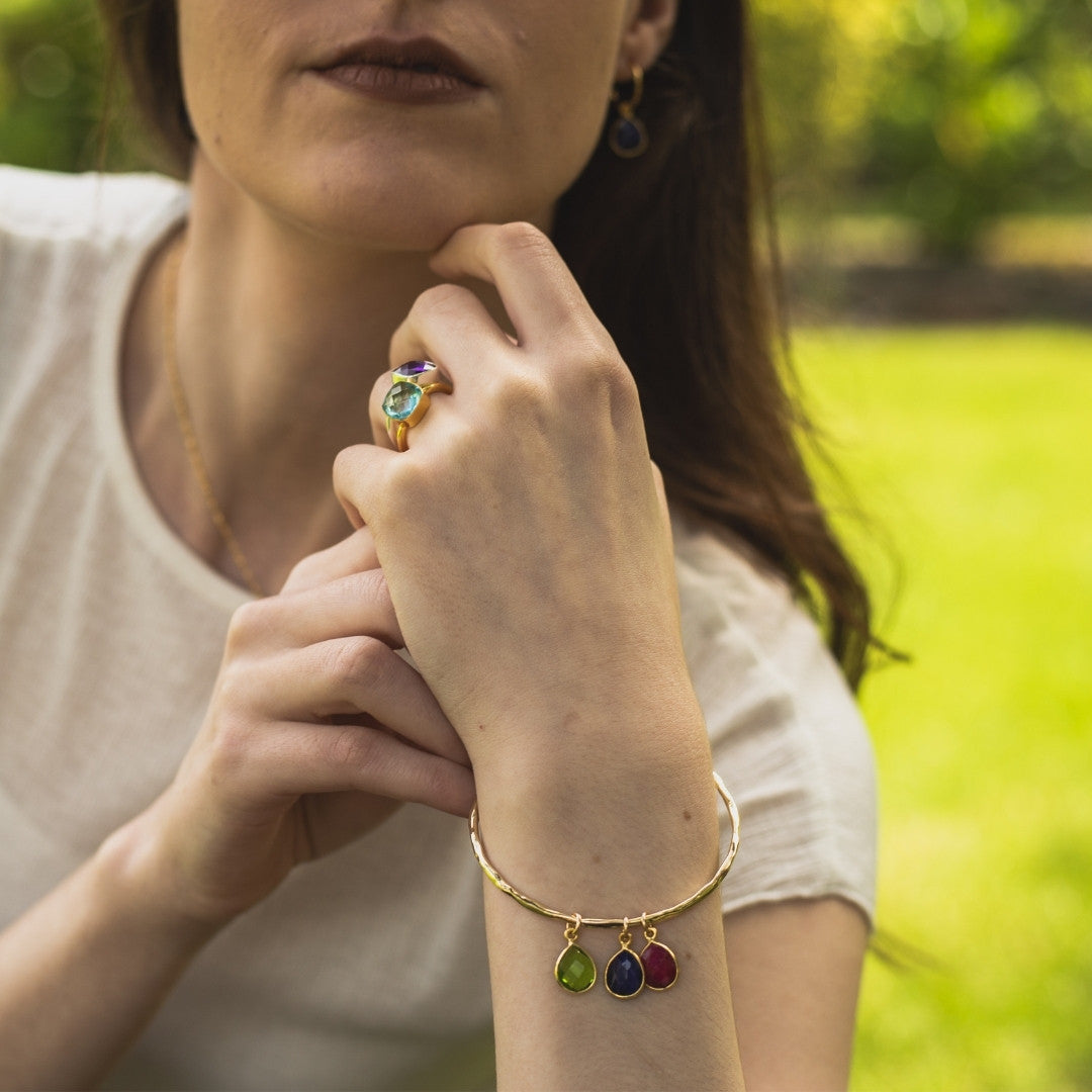 model wearing gold charm bangle with three birthstones