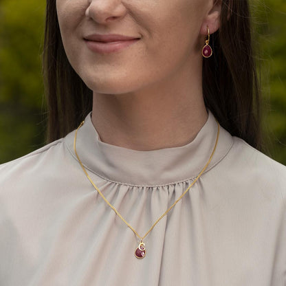 model wearing ruby drop hoop earrings and necklace in gold 