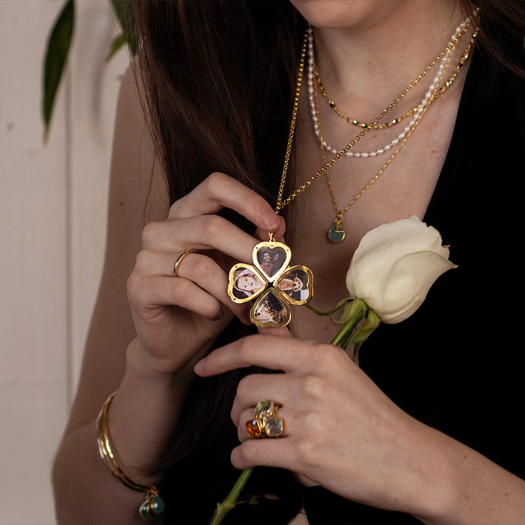 women modelling an opened four photo heart locket in gold