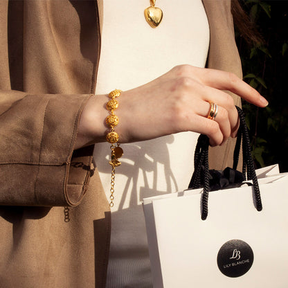women modelling gold memory keeper bracelet holding white lily blanche gift bag