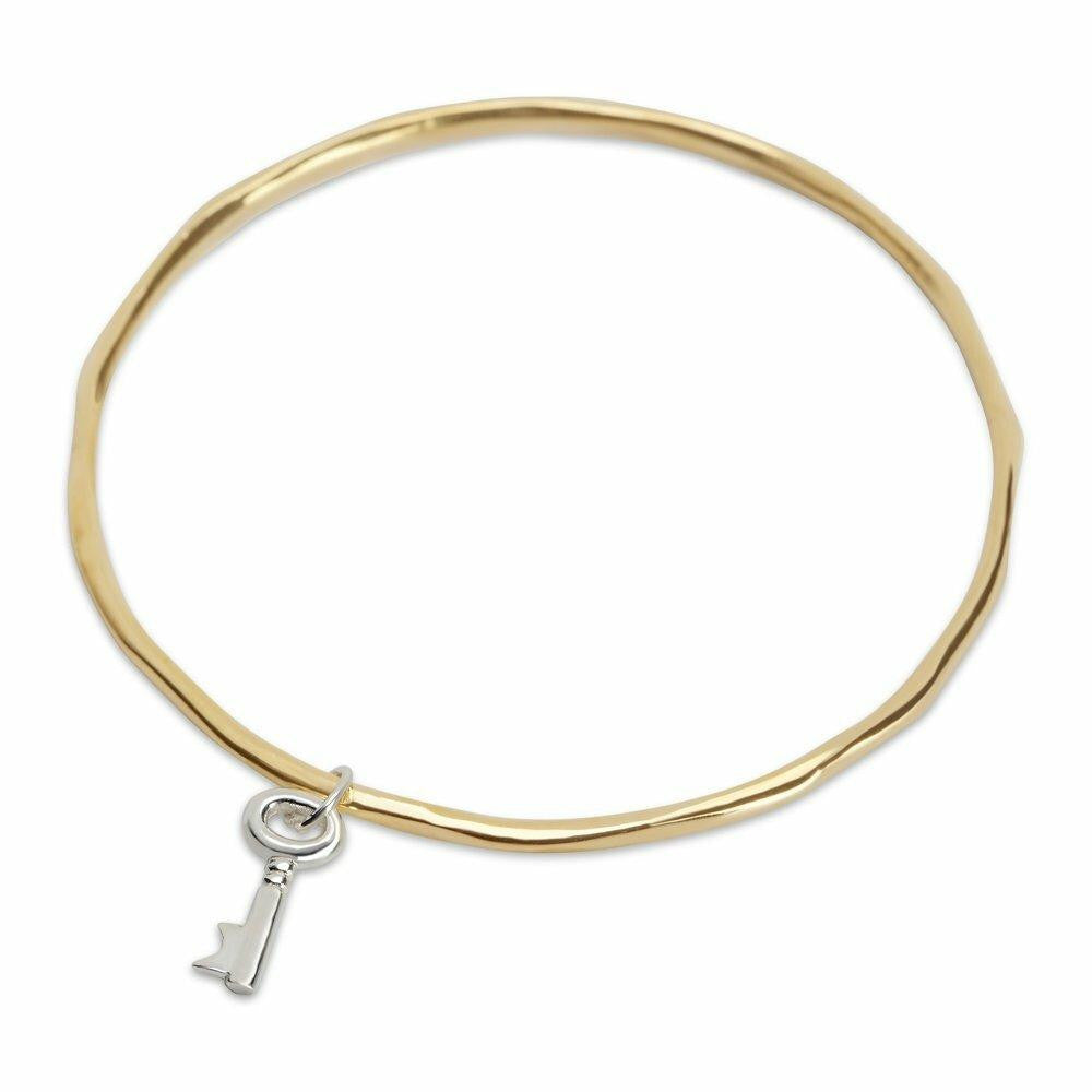 key bangle in gold with silver key charm on a white background