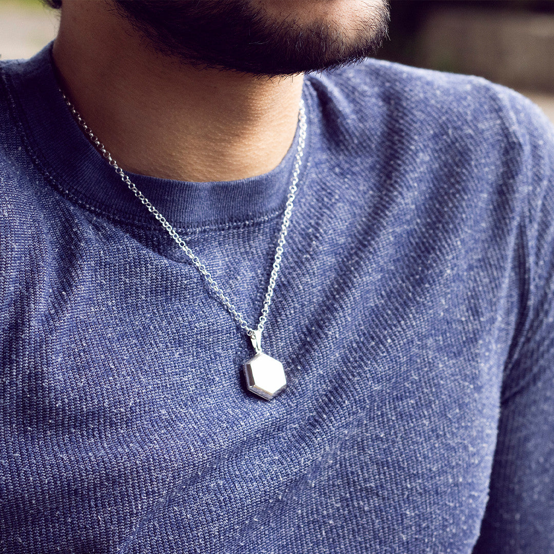 closeup of model wearing men's hexagon locket necklace in silver 