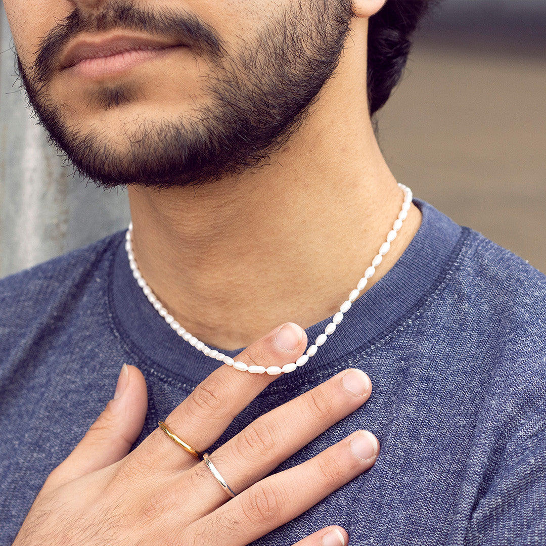 close up of model wearing men's seed pearl necklace 