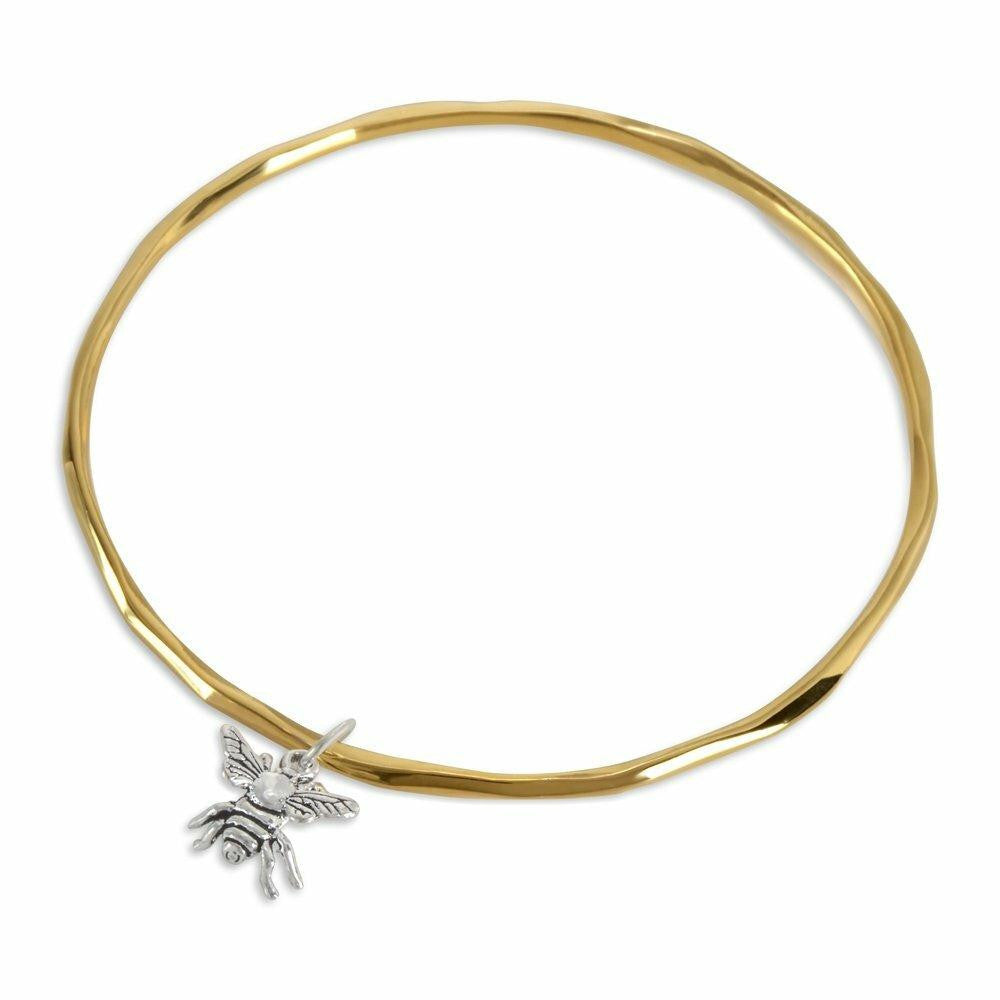 gold bangle in gold with silver bee charm on a white background