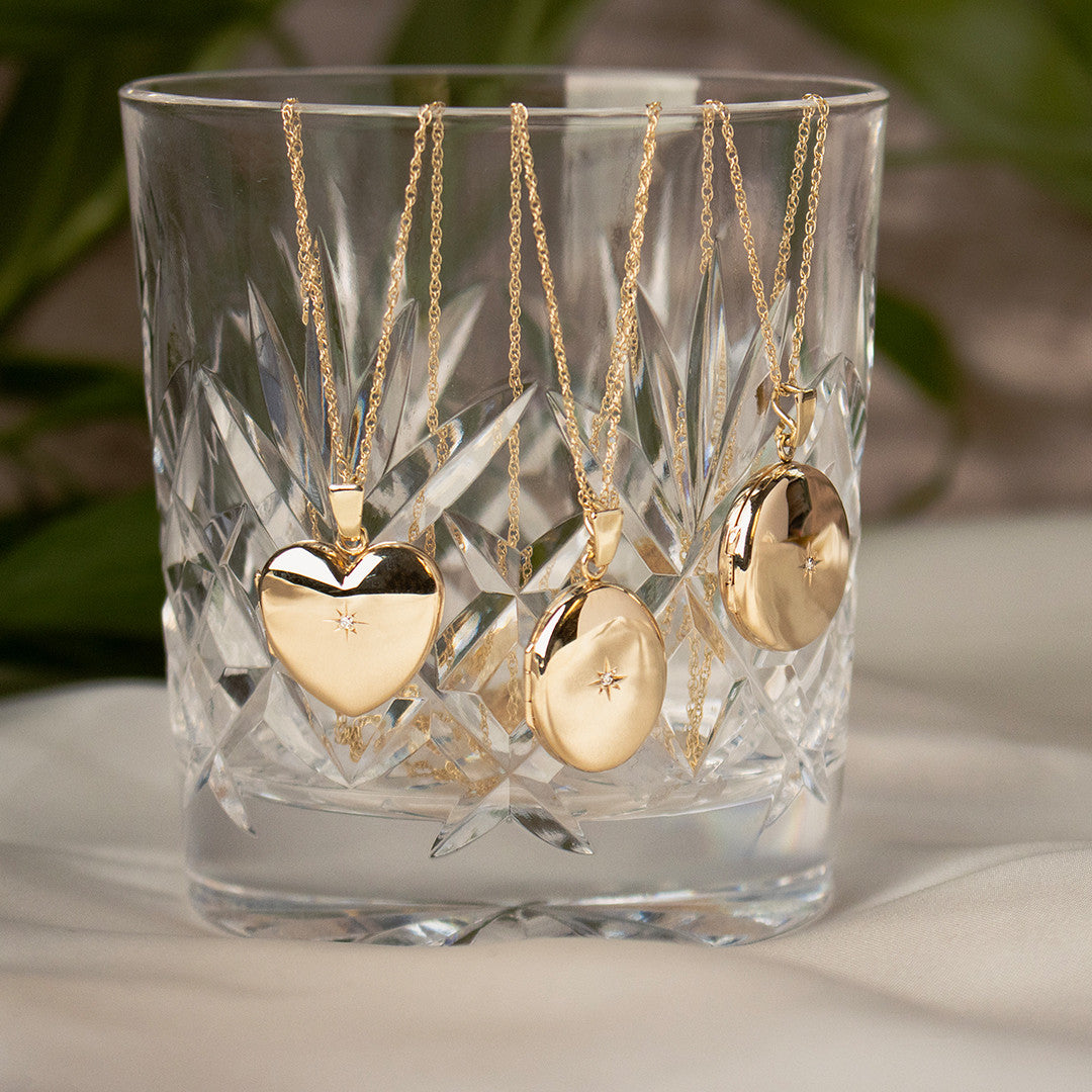 diamond oval, heart and round lockets in gold hanging out of glass
