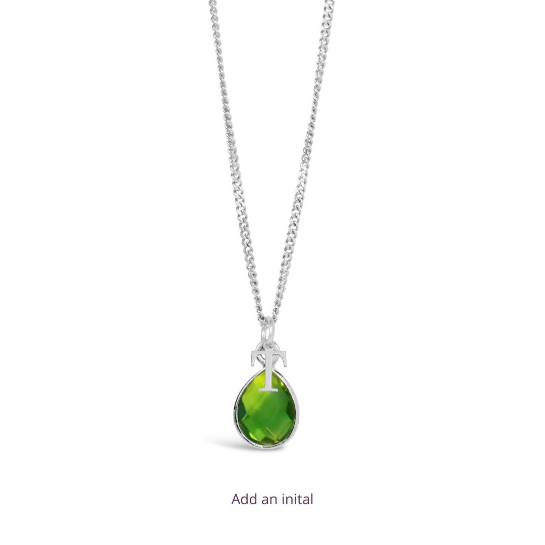 peridot charm necklace in silver with initial charm attached on a white background