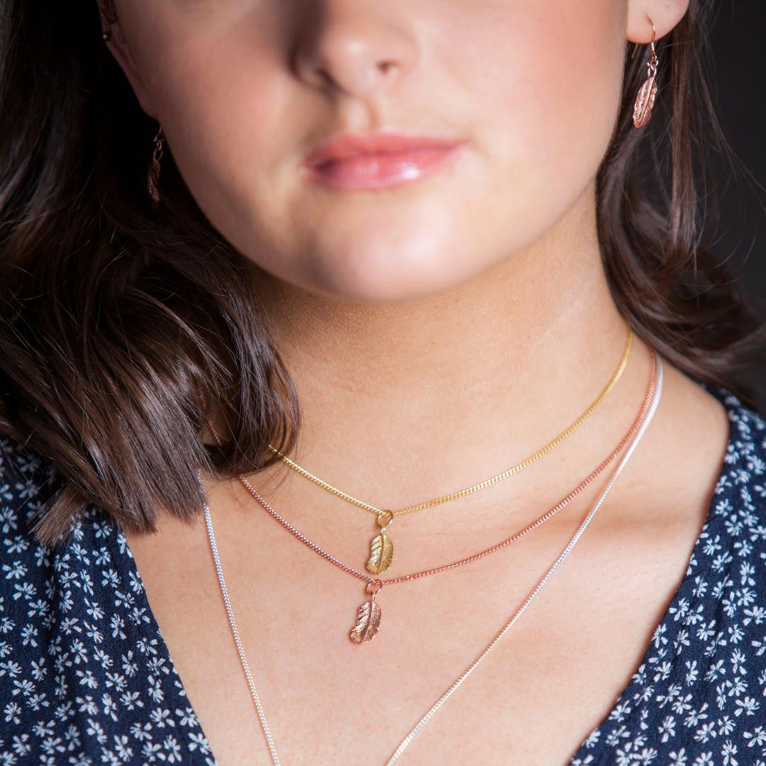 close up of model wearing feather pendant in rose gold 