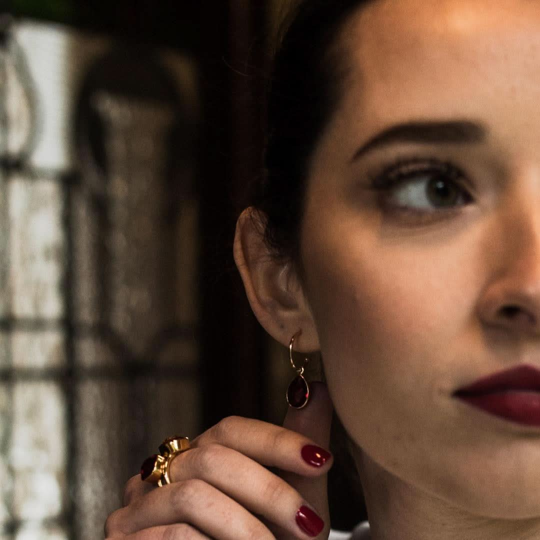 model wearing garnet drop hoop earrings in gold