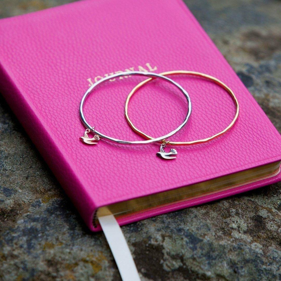 two bird bangles sitting on a note book 