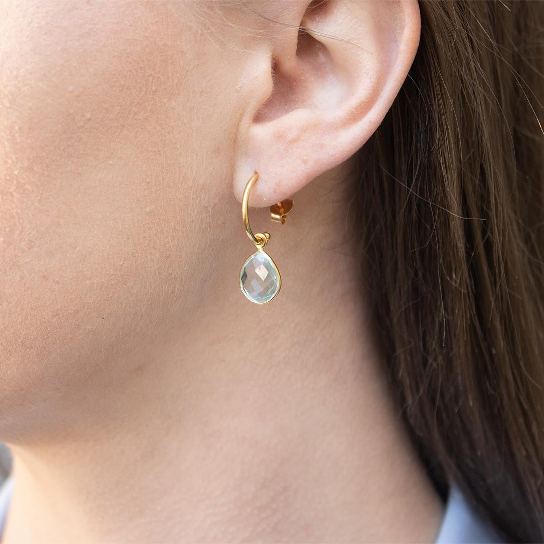 model wearing blue topaz drop hoop earrings in gold
