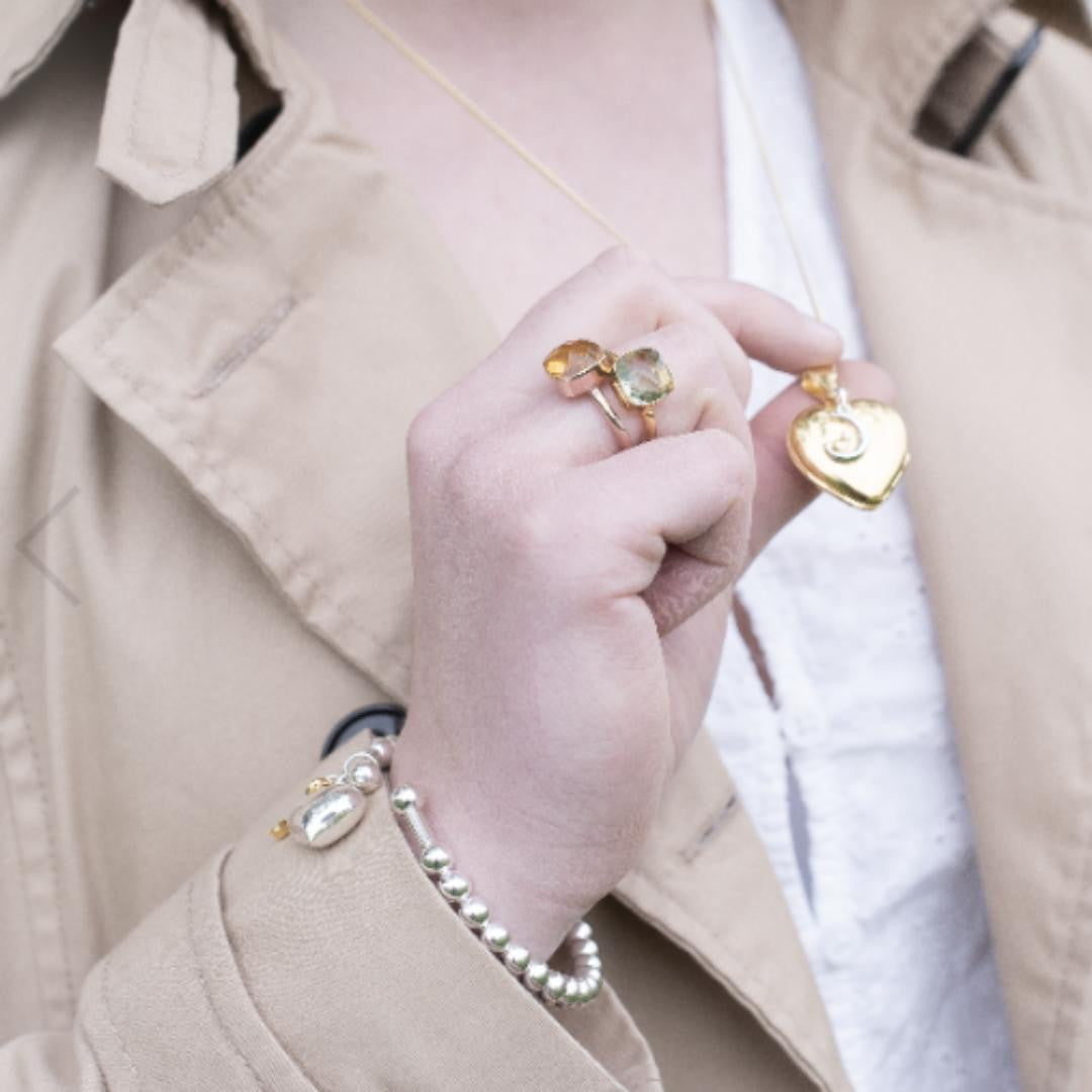 model in coat holding gold heart shaped locket with moon charm