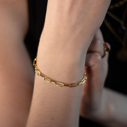 close up of model wearing paperclip chain bracelet in gold