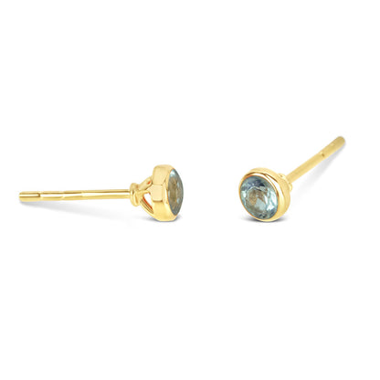 Blue topaz mini stud earrings in gold facing the side on a white background