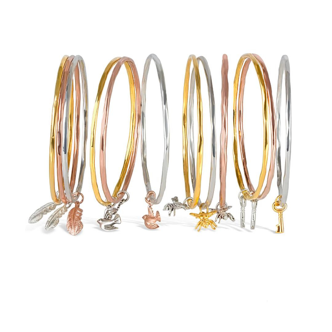 rose gold, silver and gold bee bangles on a white background
