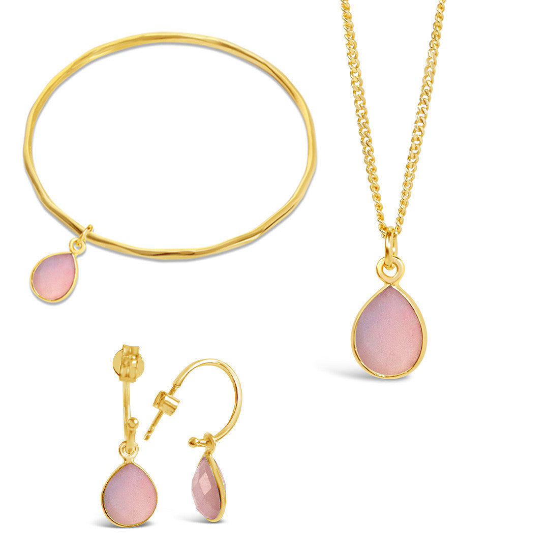 pink opal gold charm bangle, necklace and drop hoop earrings on a white background