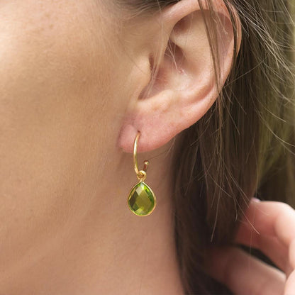 close up of female model wearing peridot drop hoop earrings in gold